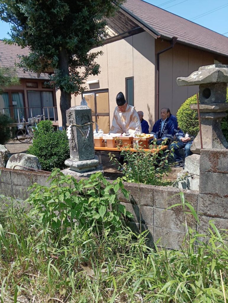 大石公民館で開催された五穀豊穣祭の神事の様子。滝尾の若宮社からお越しの長山宮司が祭壇の前で儀式を執り行い、参加者が見守る場面。