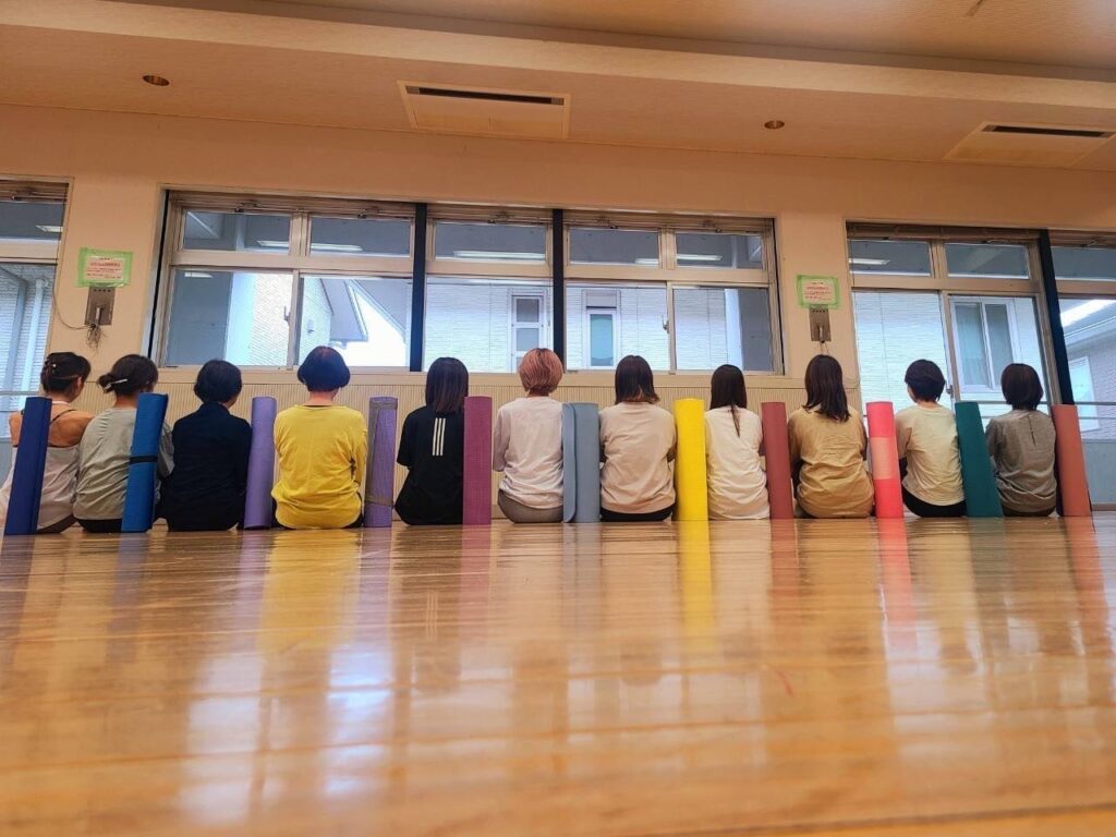 ピラティス教室の様子の写真。生徒のみなさんが座っています。
