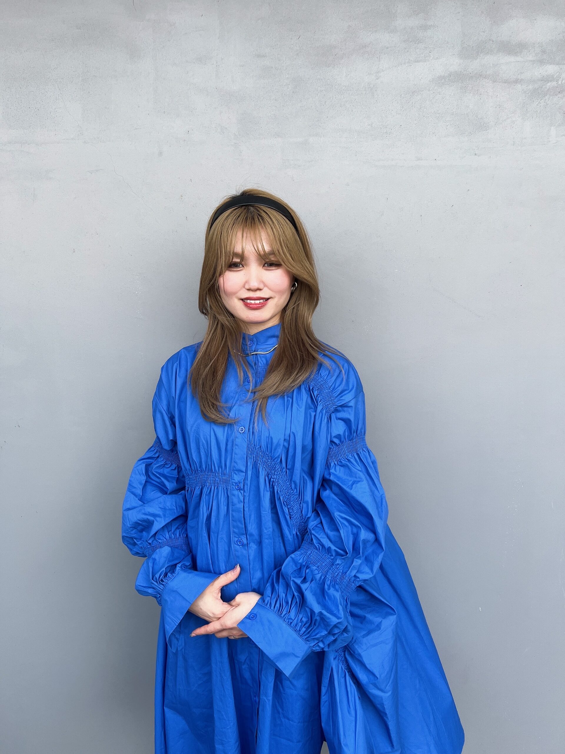 トップデザイナー「スーリール南大分」の中邑 瑠莉華（なかむら るりか）さん。青い洋服に長い髪をした笑顔の女性です。