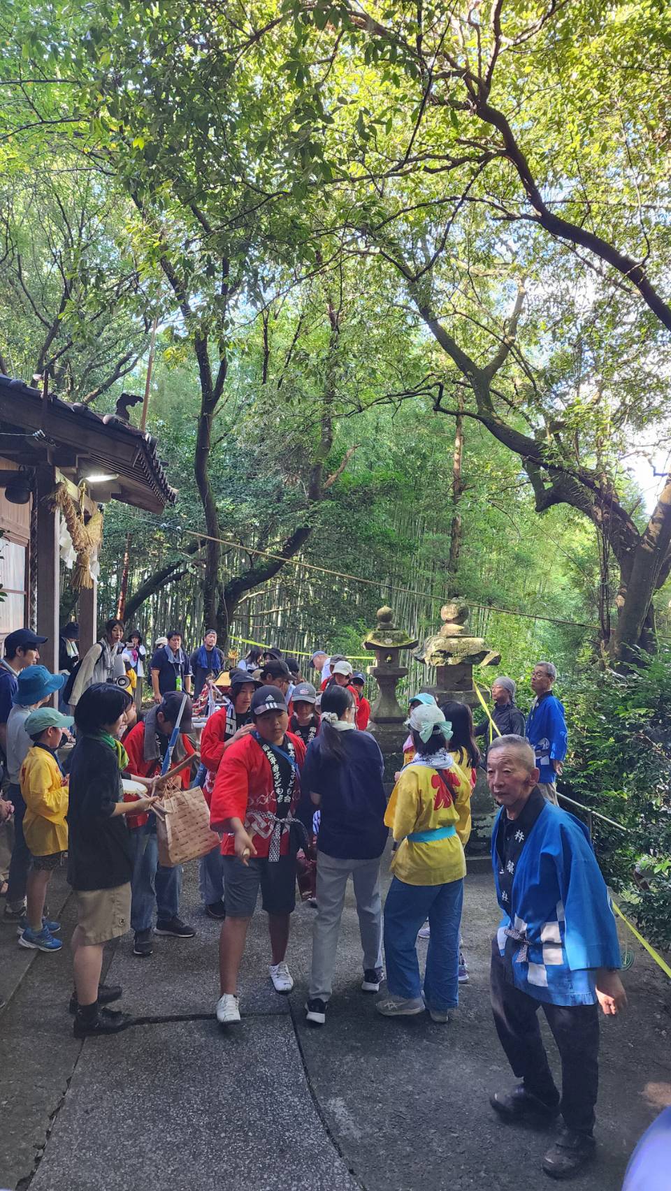 南太平寺・杵築社でので子ども神輿巡行の出発前の様子。参加者たちは赤、黄、青の法被を着ています。保護者の方々も一緒に写っています。