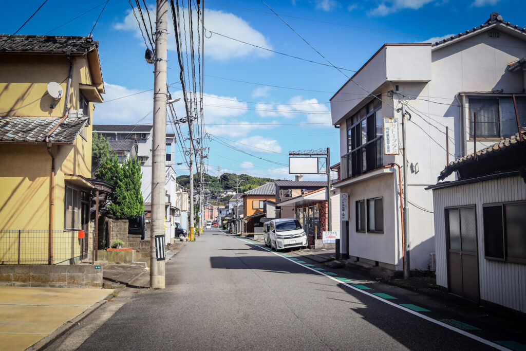 南大分・三ケ田町の目抜き通り。晴天の下、住宅や商店が並ぶ静かな街並み