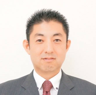 「人生しくじらない教室」のセミナー講師・秦邦仁さんの写真。白い背景の前でダークスーツに白いシャツ、えんじ色のドット柄ネクタイを着用し、落ち着いた表情で正面を向いている。シンプルで清潔感のある構図が、講師としての誠実さと専門性を伝えるビジネスプロフィール写真。