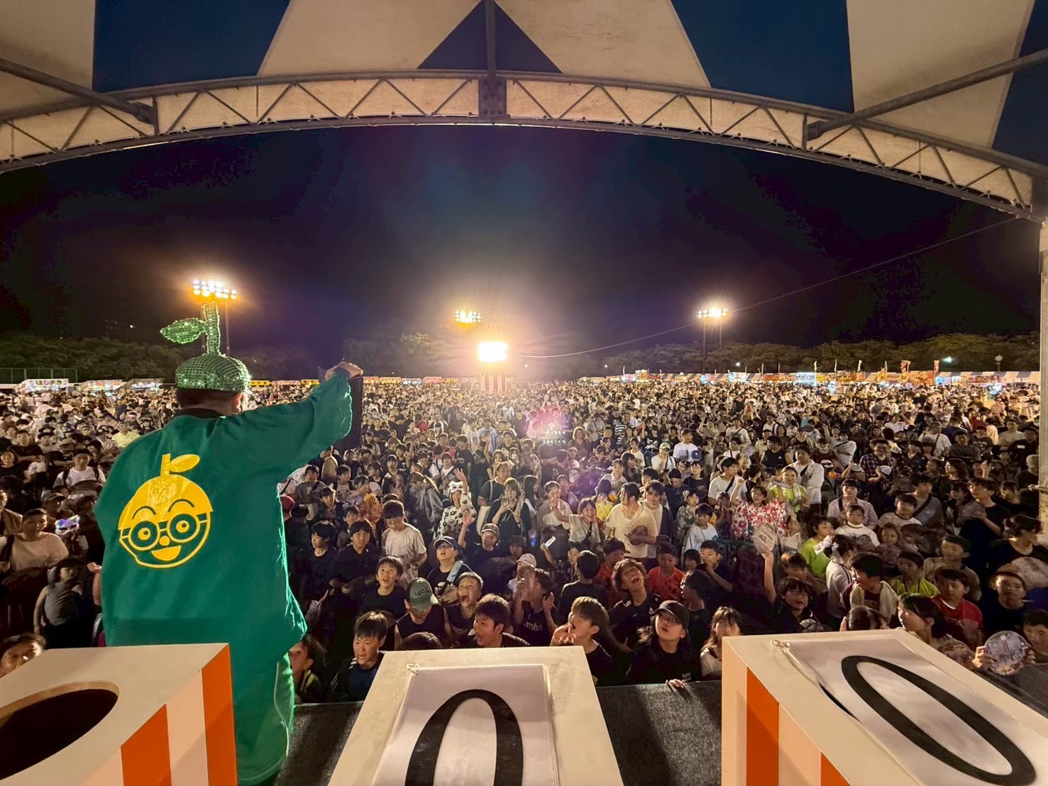 みなみおおいた夏祭りの様子。ステージ側からの視点で大勢の観客と司会者が写っています。