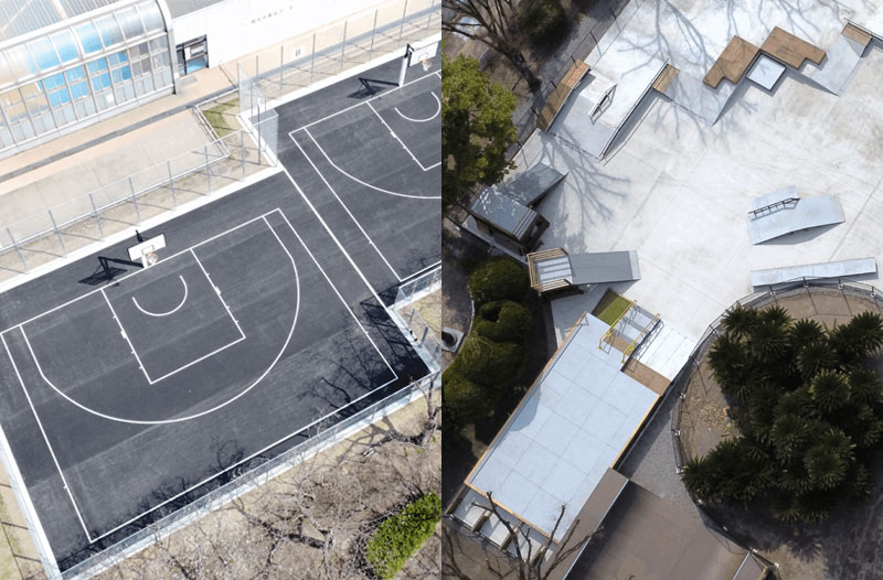 上空から撮影された、南大分スポーツパークの3×3バスケットボールコートと大手公園スケートボードパークの写真。左側には黒い舗装面に白線が引かれた2面の3×3バスケットコートが並び、フェンスと建物が隣接している。右側には複数のランプやレールが配置されたスケートボードパークが広がり、周囲には木々や植栽が見える。2つのスポーツ施設が隣接して配置されている様子が俯瞰で捉えられている。